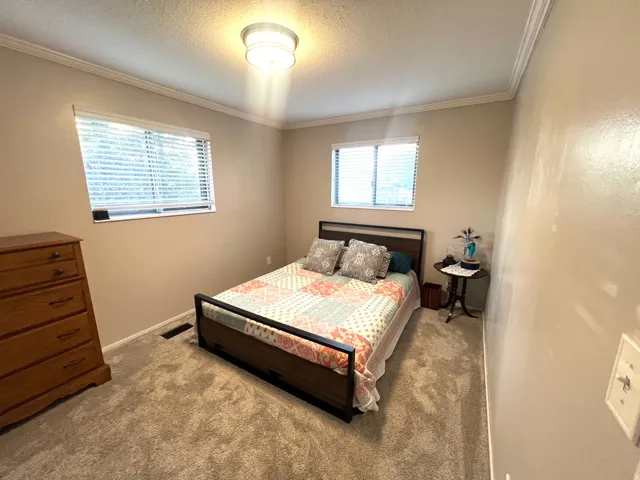 Neutral-toned walls with crown molding, two windows with blinds, and recessed lighting