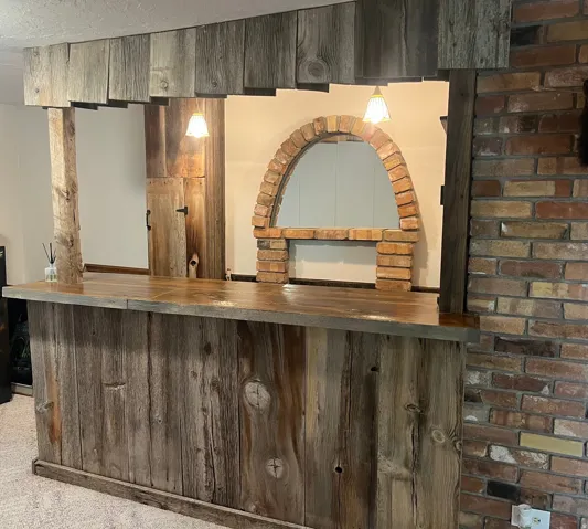 Wood-paneled bar featuring a wood-finish countertop, brick archway detail, and pendant lighting