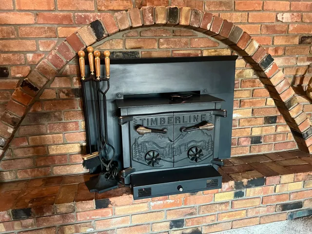 Charming brick fireplace featuring a traditional arched opening, cast iron insert stove with decorative detailing, and wrought iron fireplace tools including poker and tongs