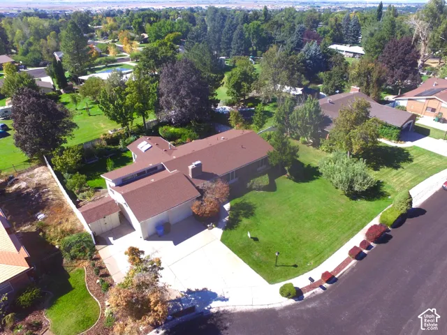 Expansive corner lot with mature trees, a manicured lawn, and lush landscaping, featuring a private driveway and a two-car garage