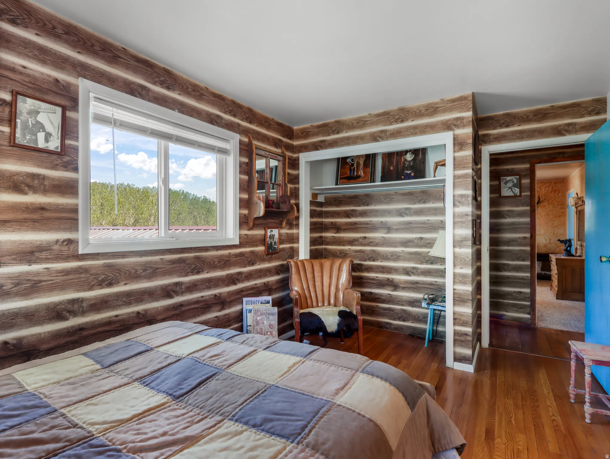 Wood-finish walls with white trim, wood-finish flooring, and a white framed window