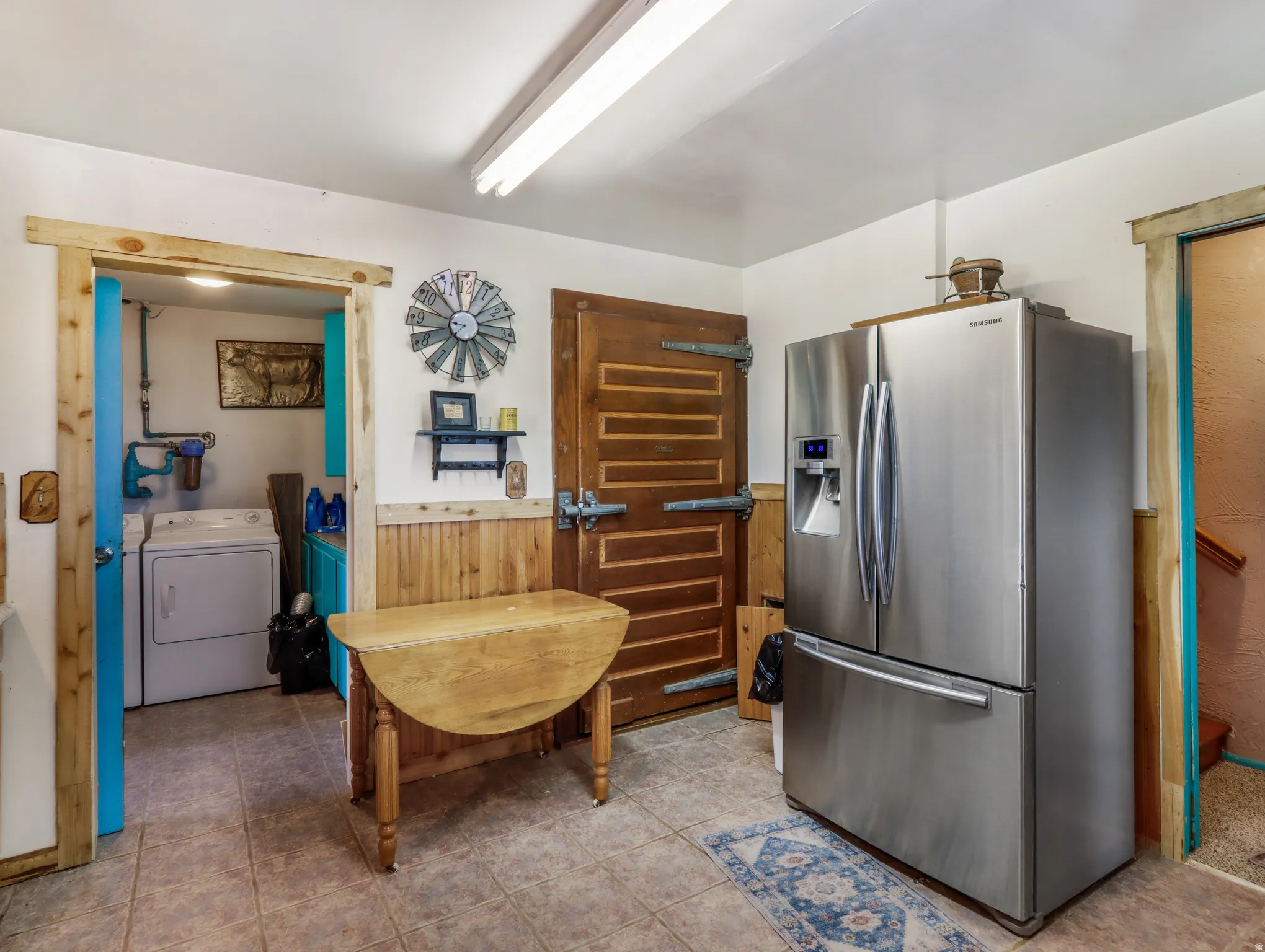 Tile flooring, wood-paneled walls, a stainless steel refrigerator, and a permanent overhead light fixture