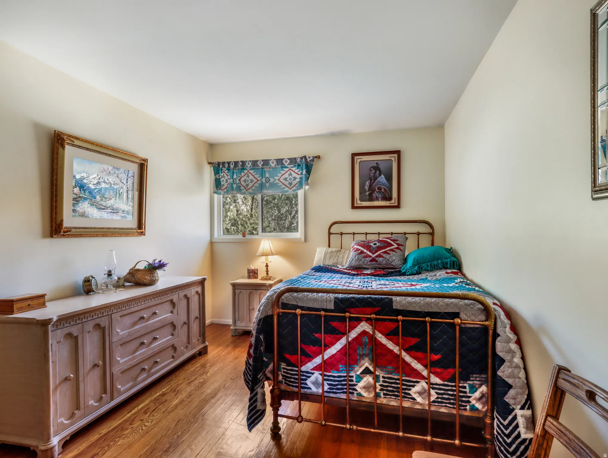 Hardwood flooring, single window, painted walls, wall-mounted light fixture, and a decorative valance