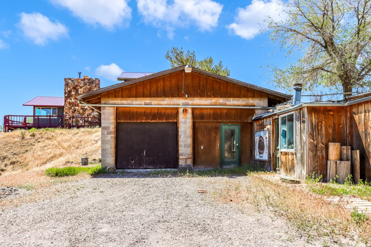 Gravel driveway leading to a two-car garage with wood-paneled siding and a concrete block foundation