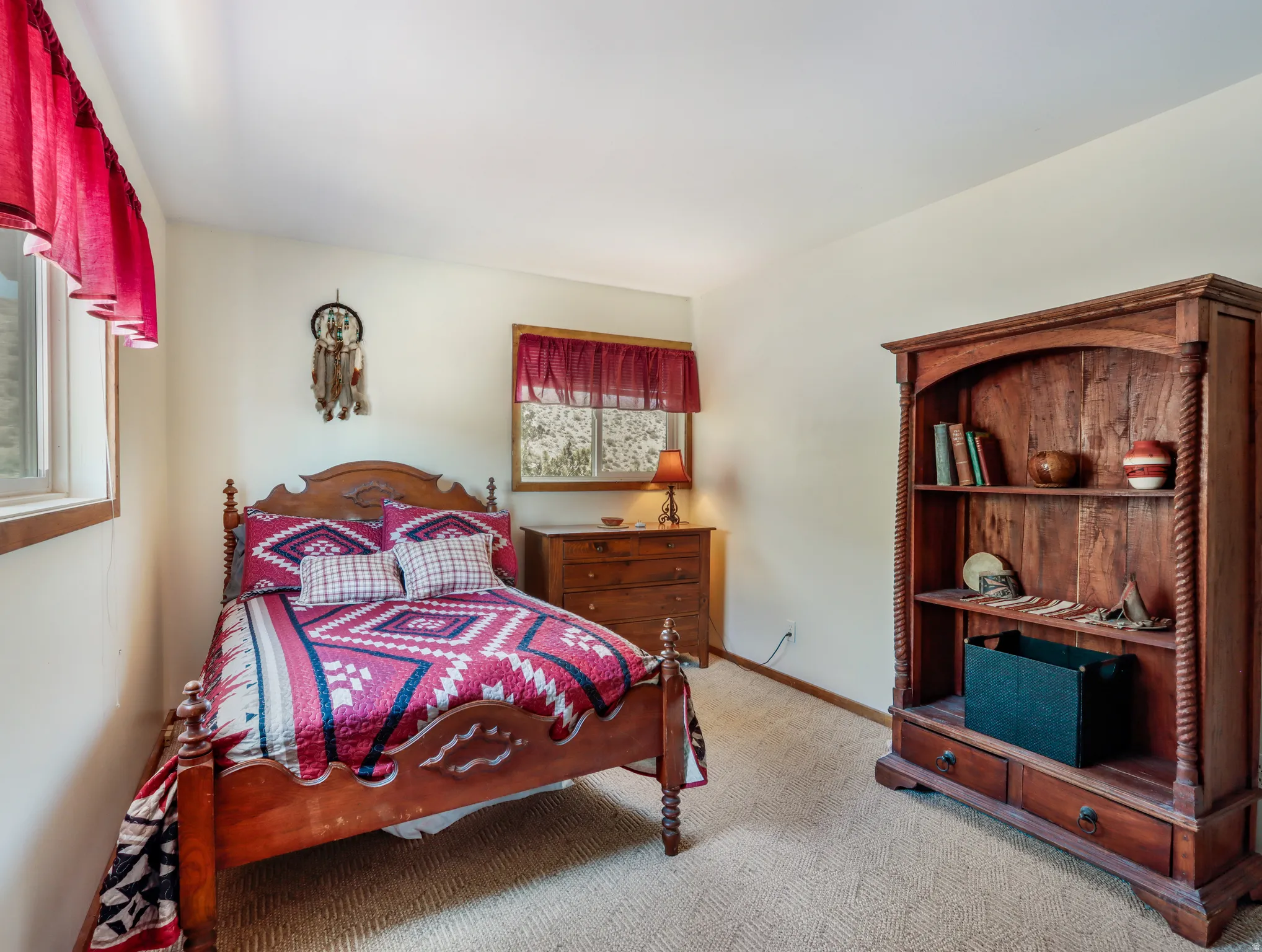 Carpeted room with two windows, a wood-frame bed, and a built-in wooden bookshelf