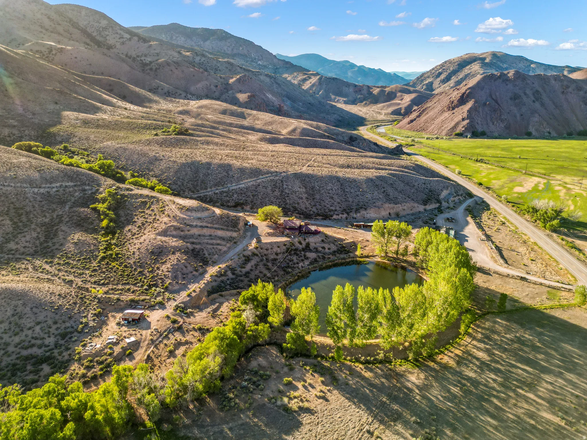 Property featuring a private pond, mature trees, mountainous terrain, and a winding road