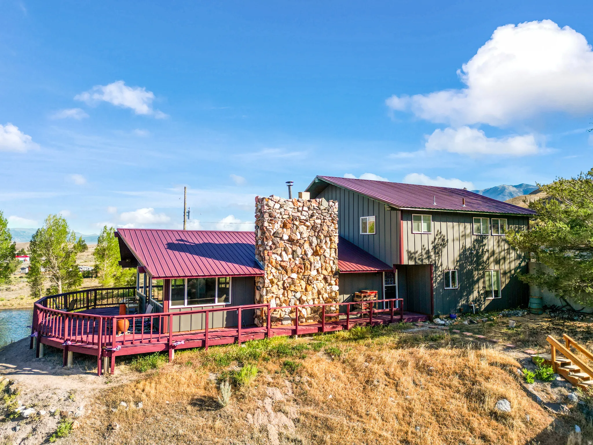Two-story residence featuring a durable metal roof, extensive exterior decking, and a prominent stone-clad chimney