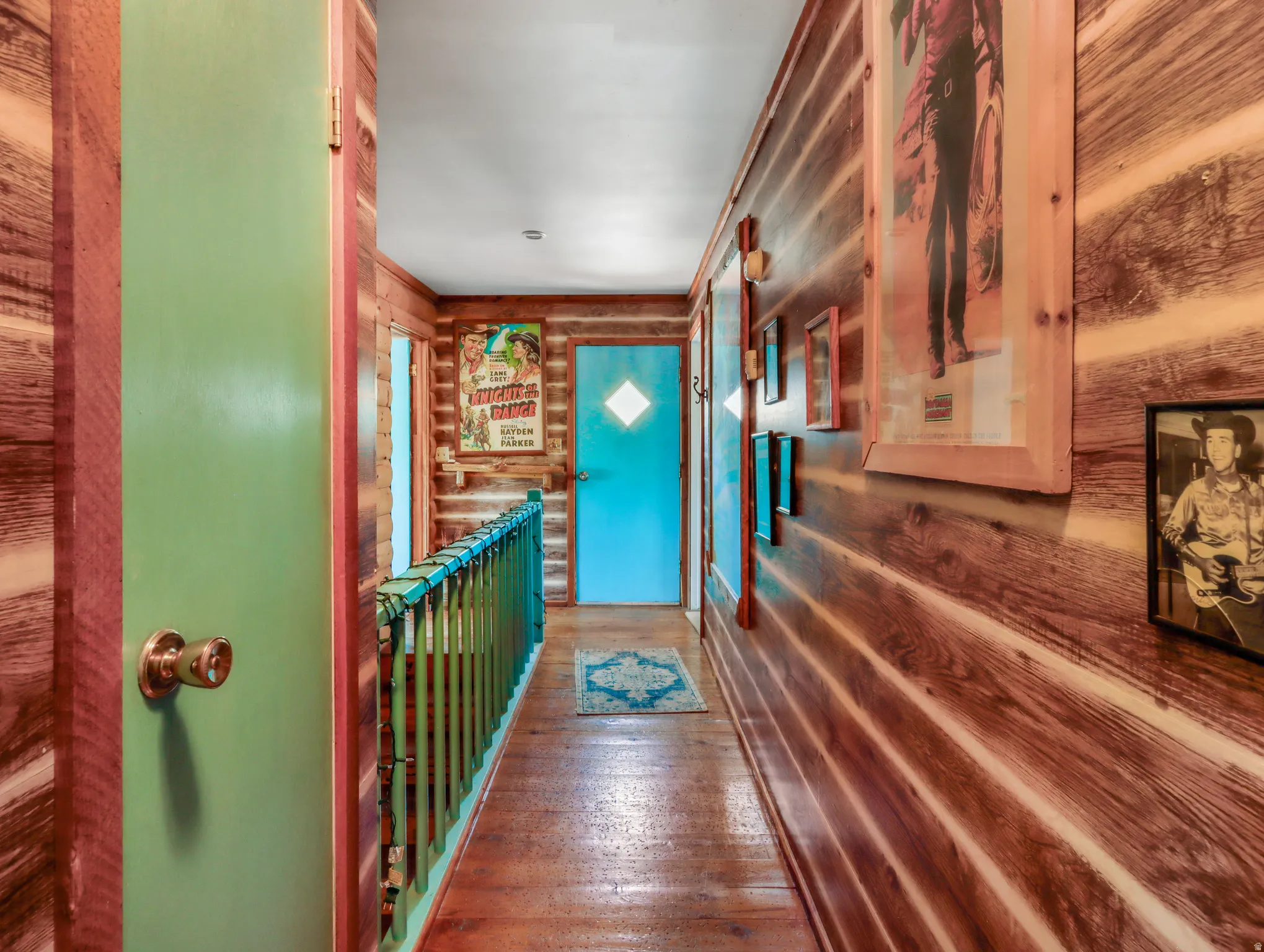 Wood-paneled hallway with wood-finish flooring, a painted baluster, and a painted door