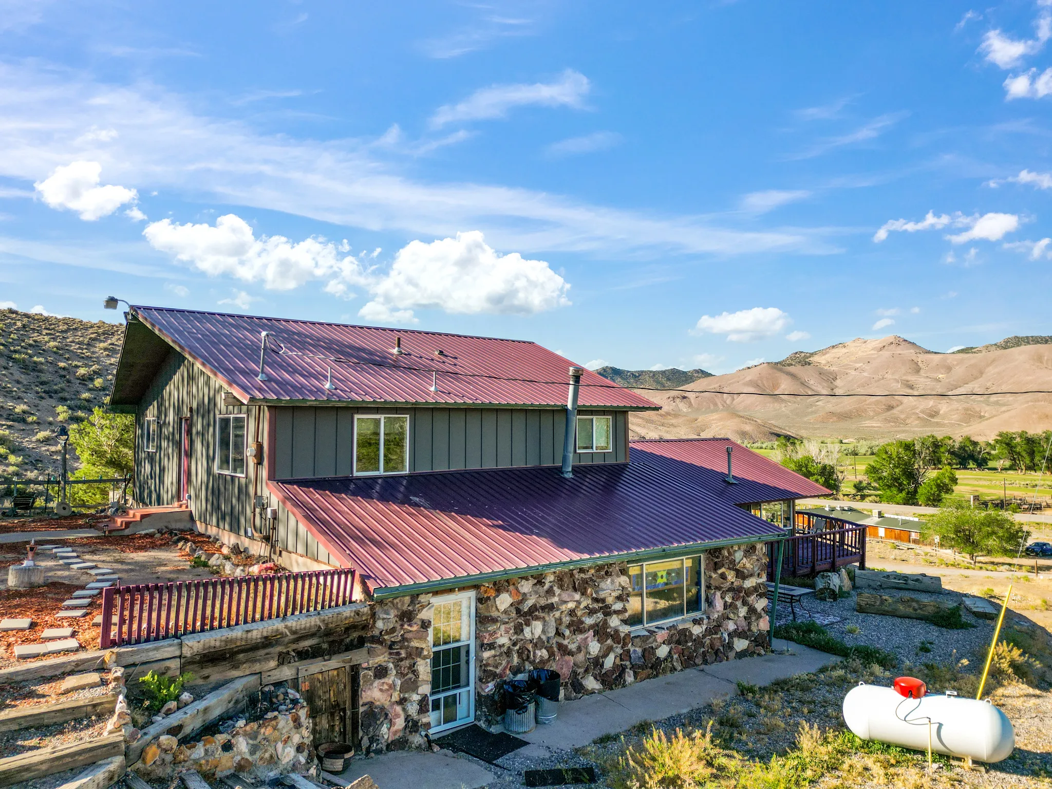 Stone and vertical siding exterior with a red metal roof