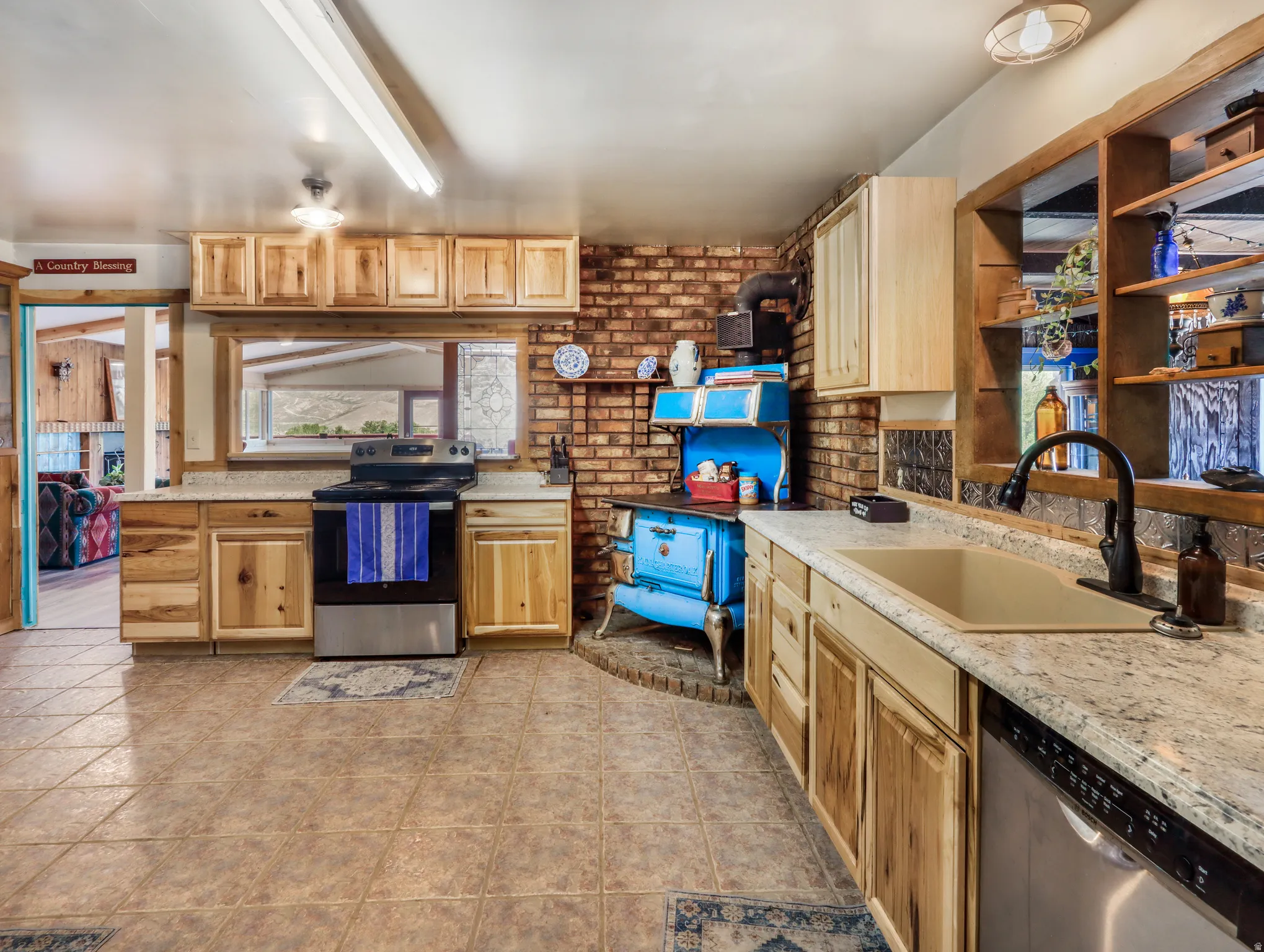 Kitchen featuring wood-finish cabinetry, tile flooring, brick accent wall, and a built-in range