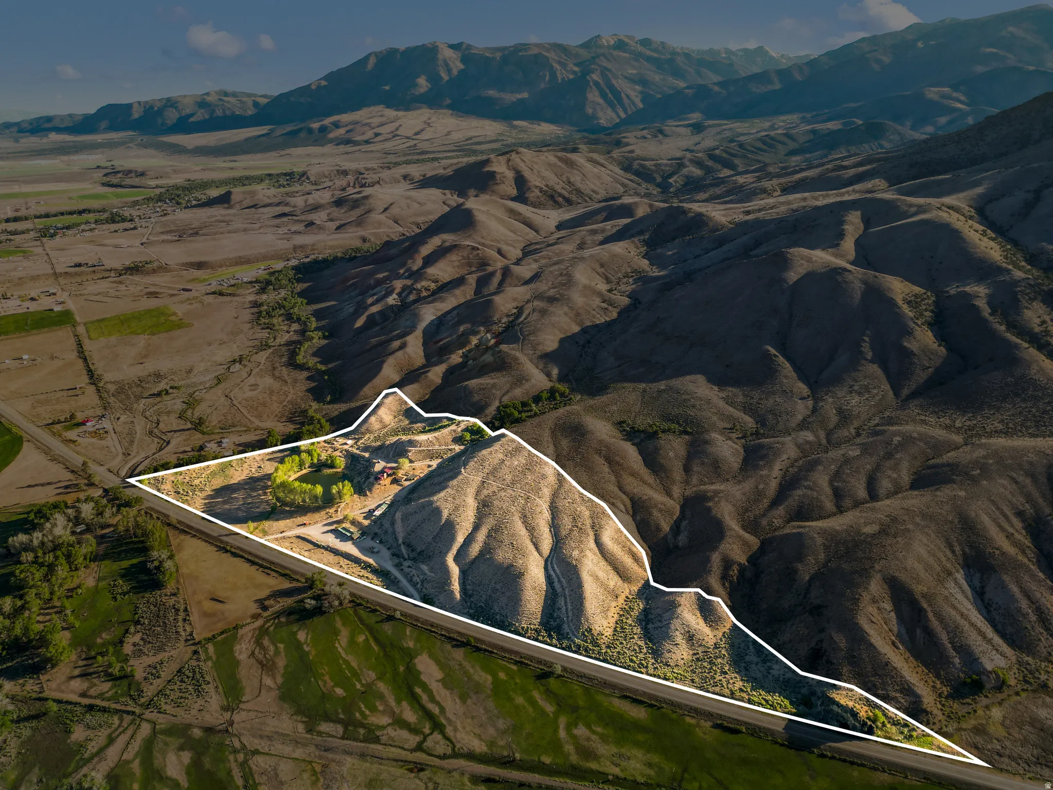 Expansive property featuring varied terrain, direct road frontage, and a mountainous backdrop
