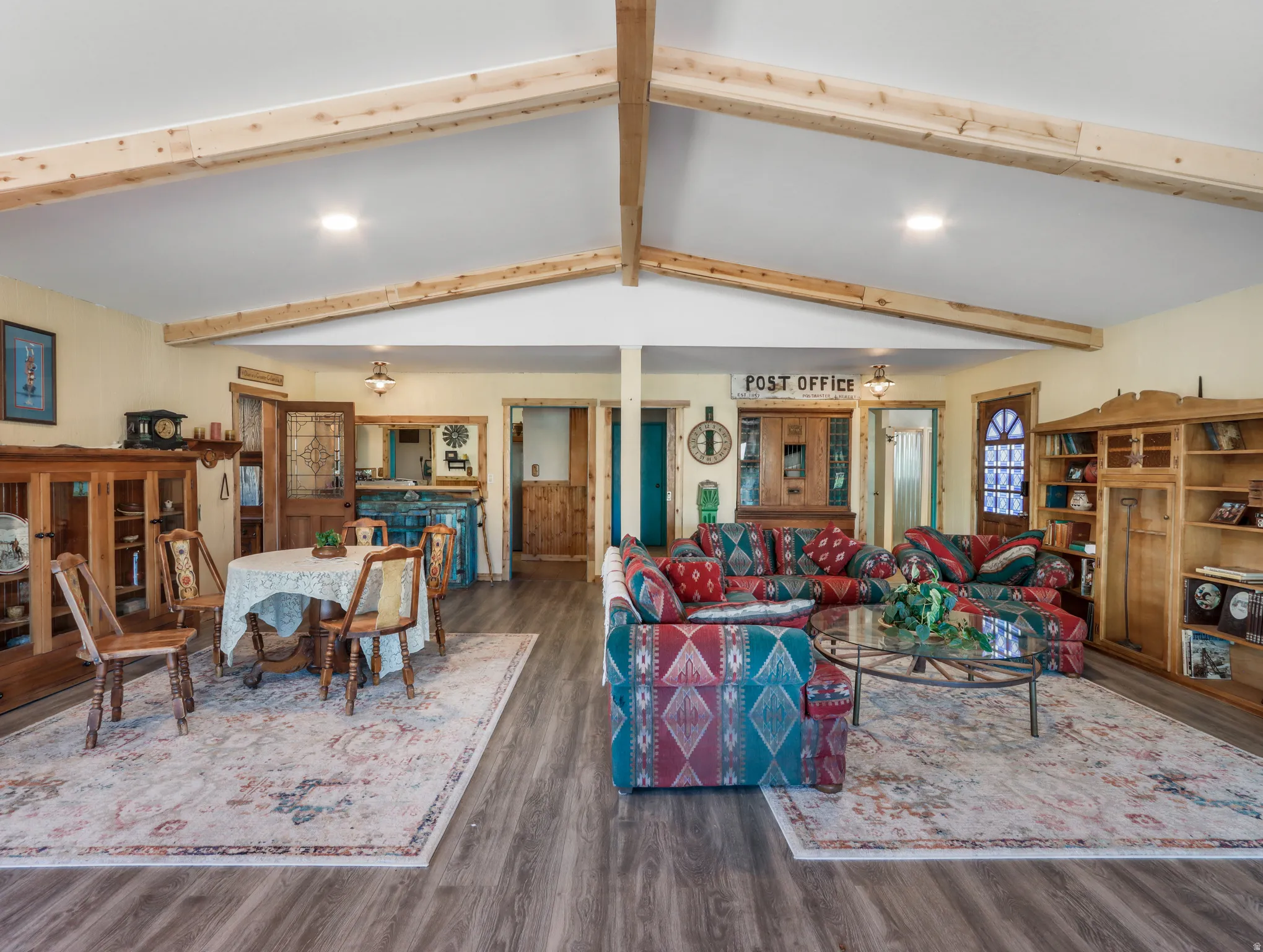Vaulted ceilings with exposed wood beams, wood-finish flooring, recessed lighting, and built-in shelving