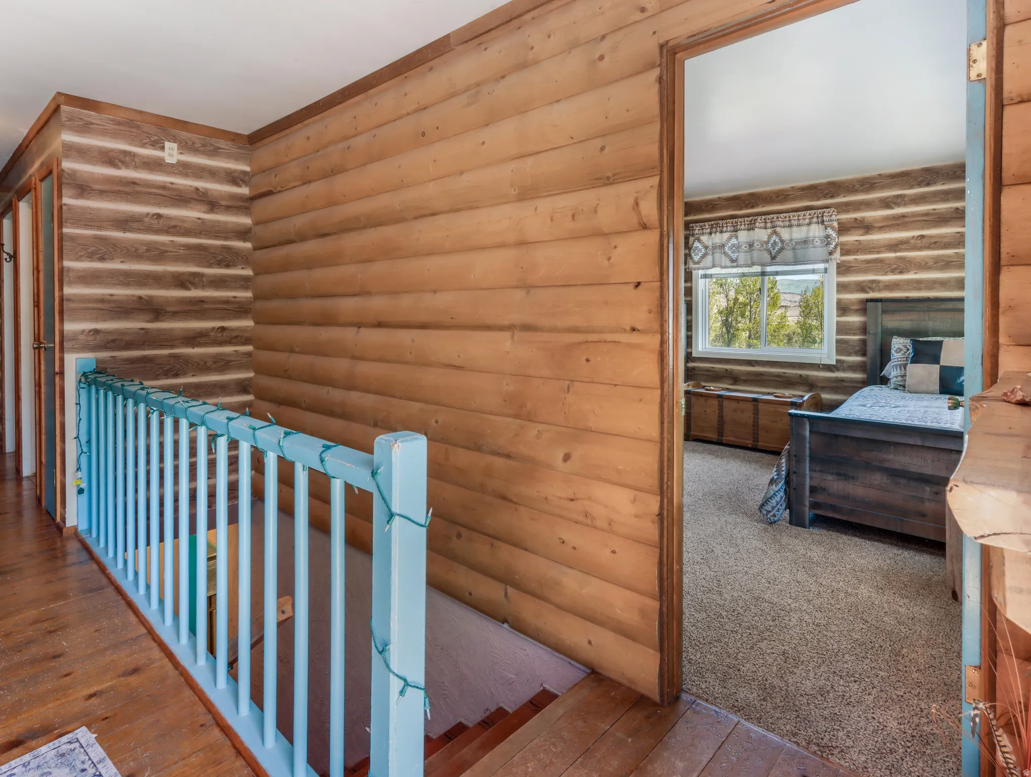 Wood-finish wall paneling, light wood flooring, and a light blue painted railing