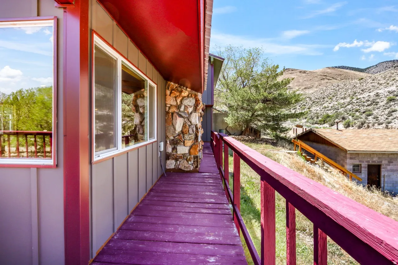 Expansive deck with wood railing, vertical siding, stone accent, and mountain scenery