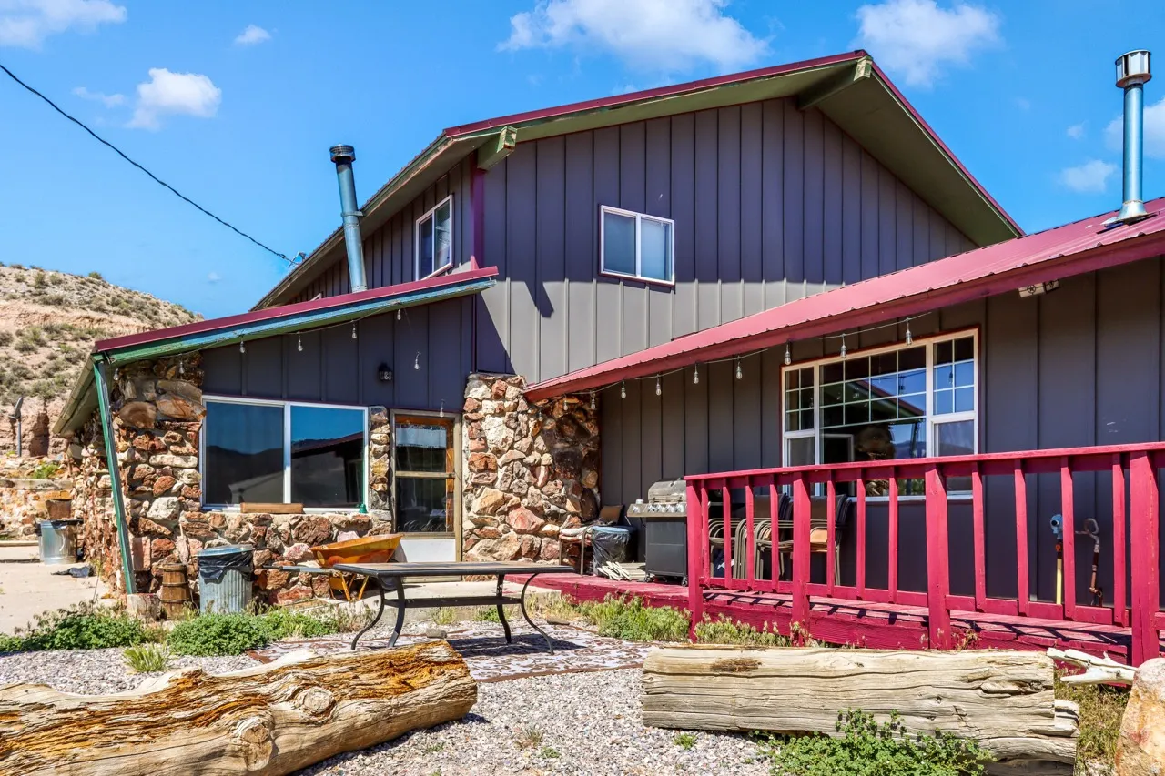 Stone and board-and-batten siding exterior with a red metal roof