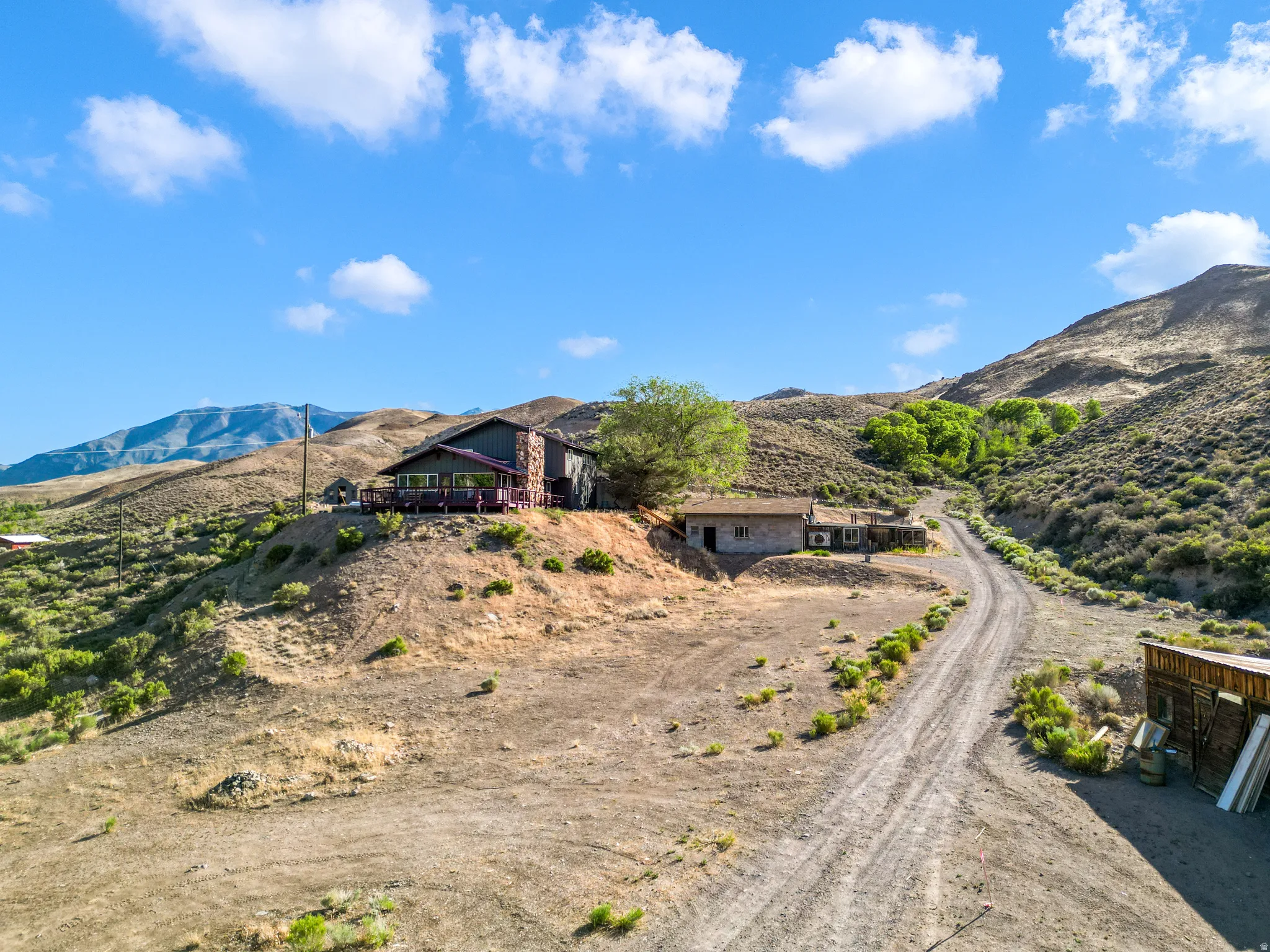 Hillside property featuring a stone and wood-sided exterior, an expansive wrap-around deck, and a detached structure