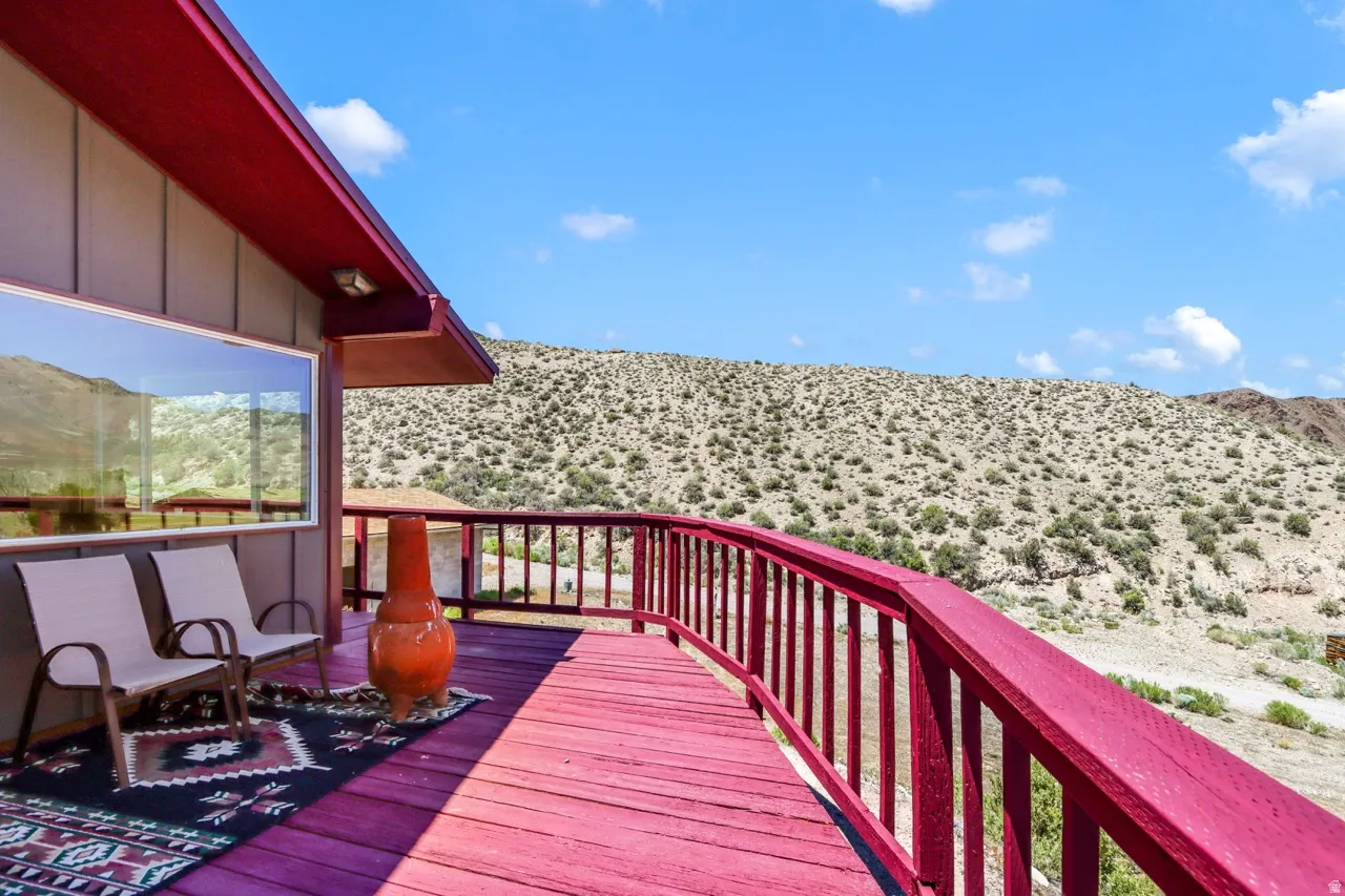 Expansive outdoor deck with a red-stained finish, a curved railing, and a desert landscape backdrop