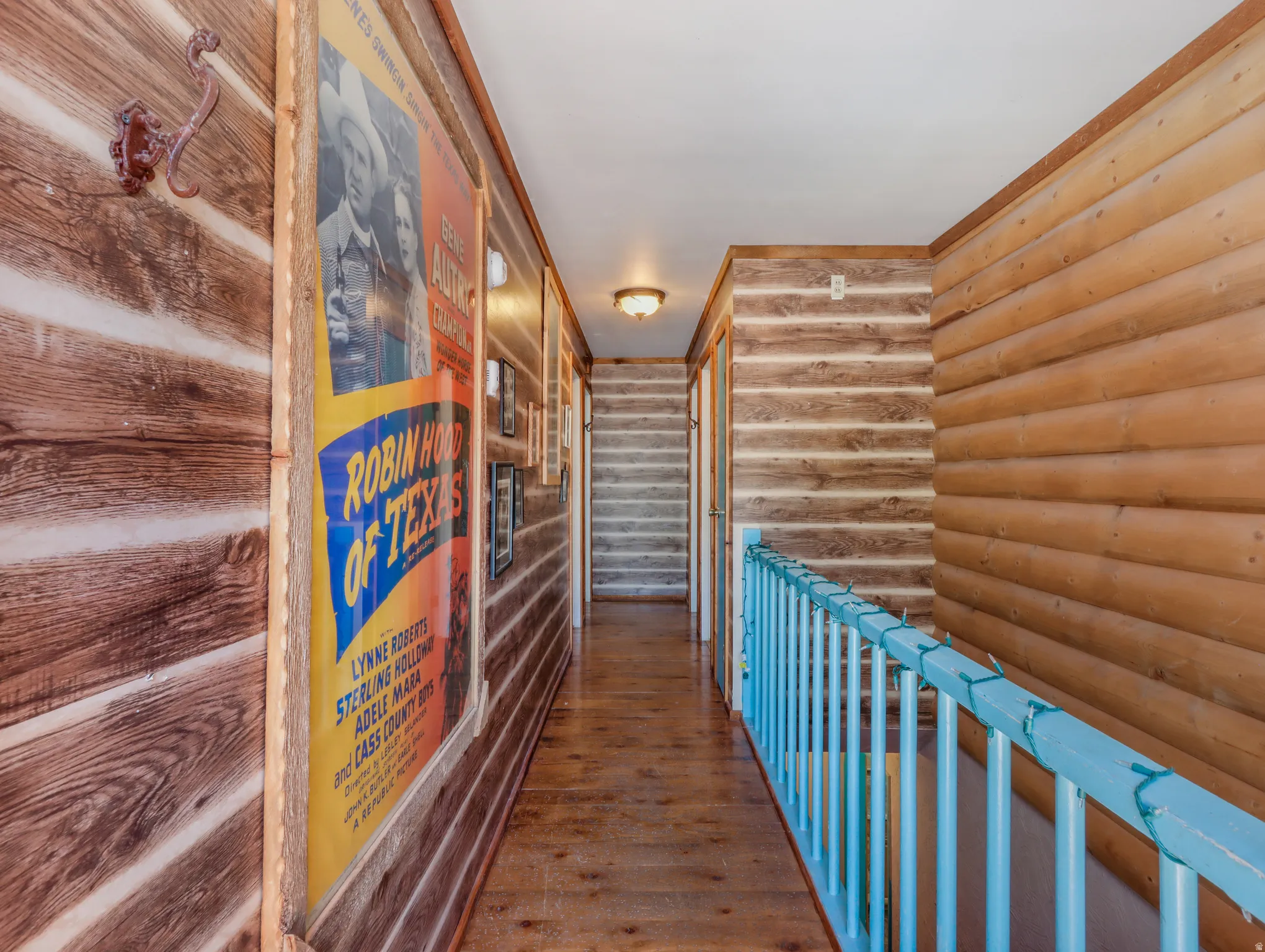Wood-paneled hallway featuring exposed beam accents, wood-finish flooring, and a painted wood railing