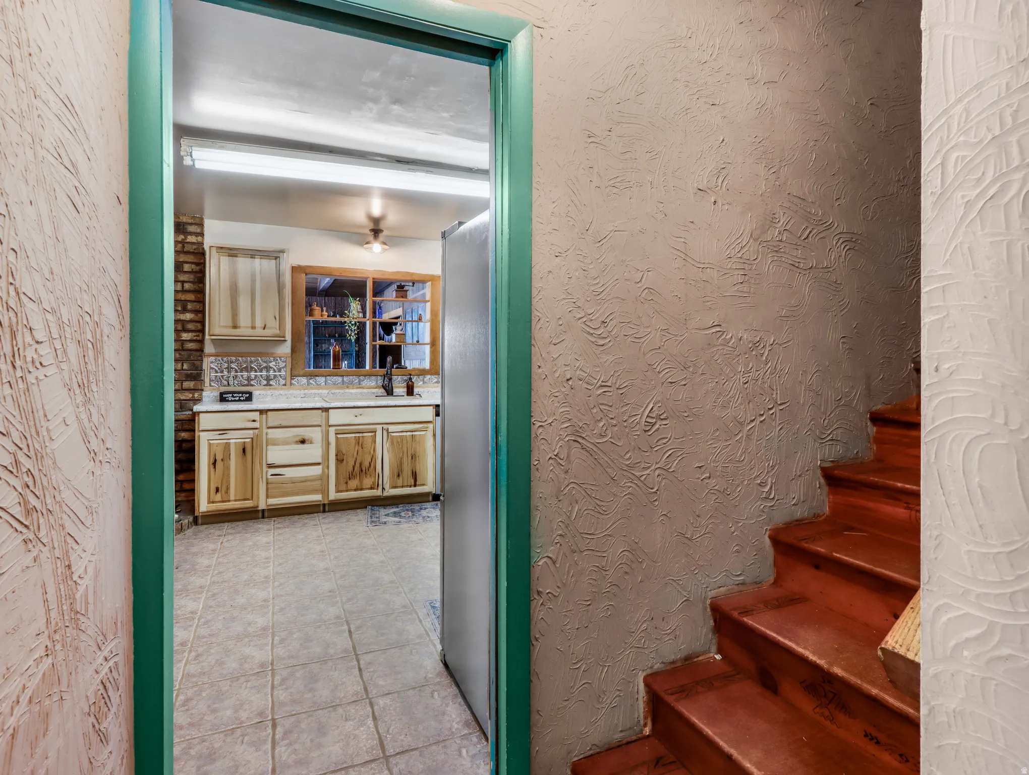 Kitchen featuring light wood cabinetry, a tile backsplash, and a window above the sink