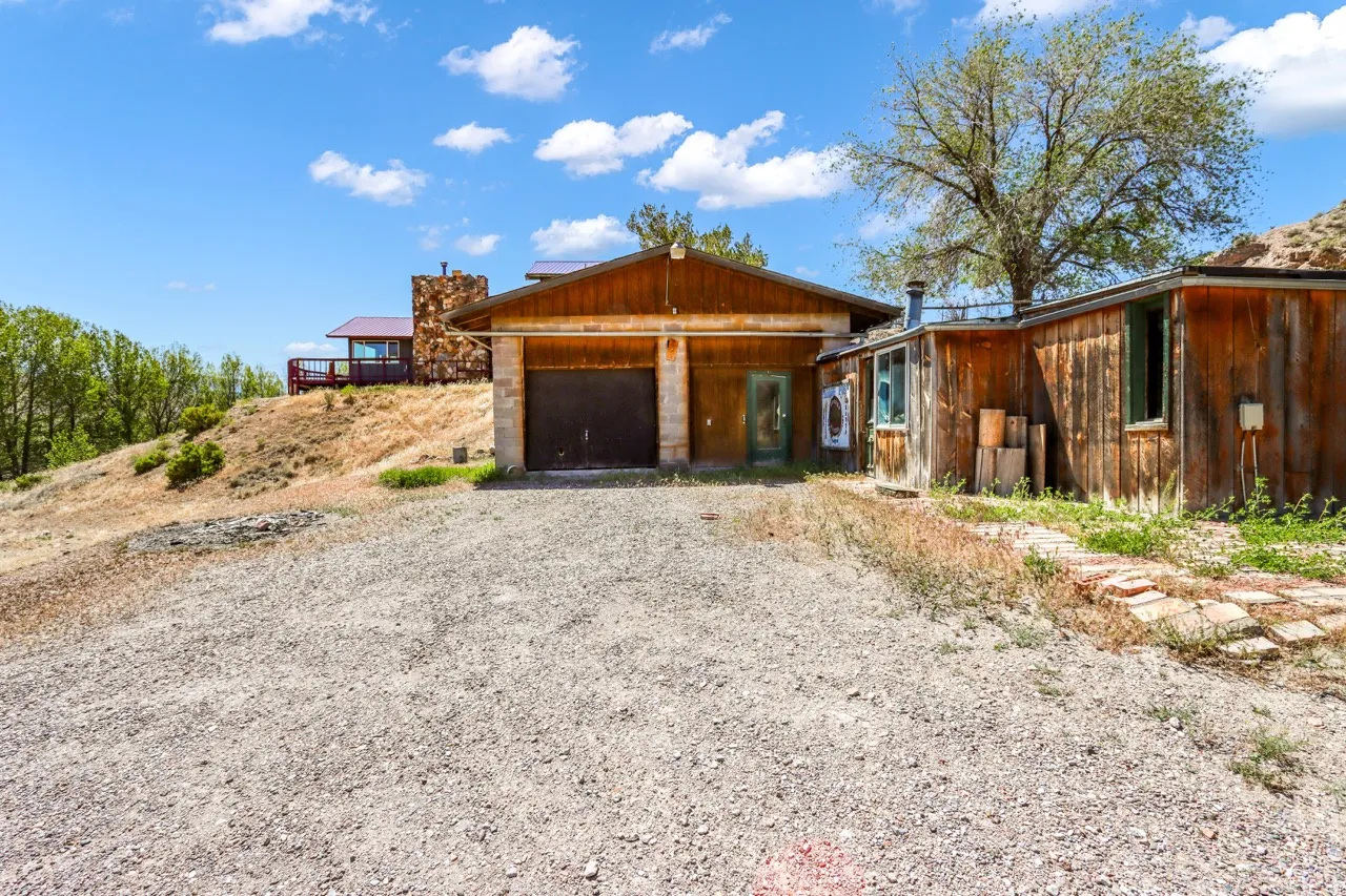 Gravel driveway with a wood-sided structure featuring a two-car garage