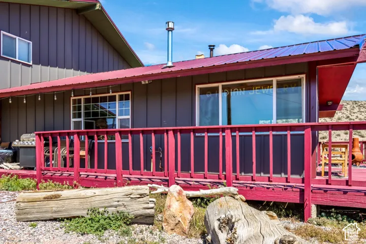 Exterior featuring gray vertical siding, a red metal roof, and a red-painted wooden deck