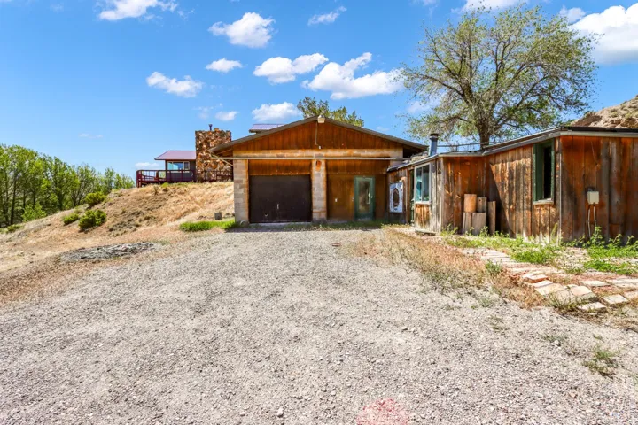 Gravel driveway with a wood-sided structure featuring a two-car garage