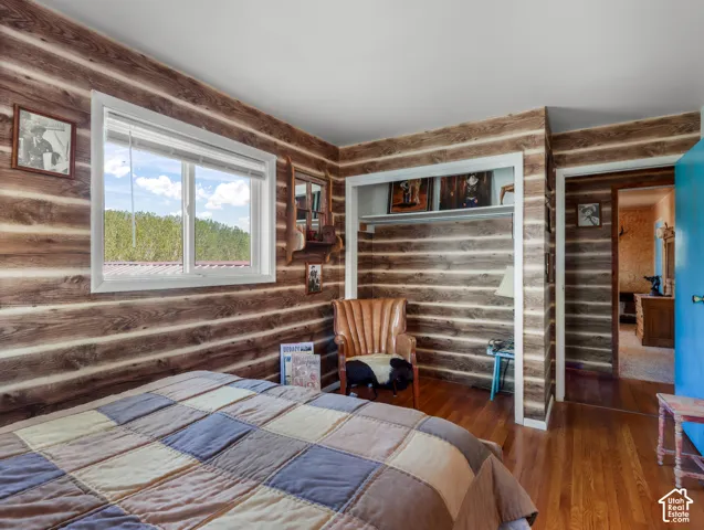 Wood-finish walls with white trim, wood-finish flooring, and a white framed window