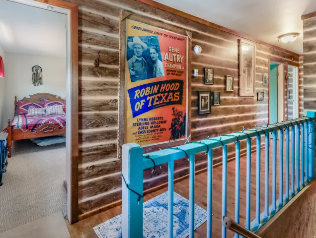 Wood-paneled hallway featuring wood-finish flooring and a painted railing