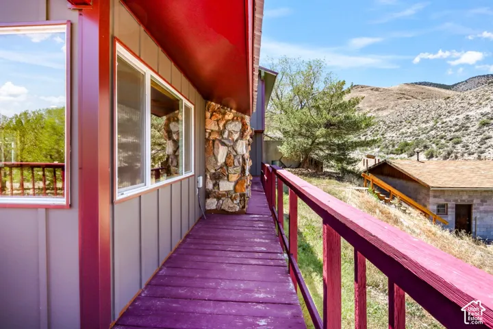 Expansive deck with wood railing, vertical siding, stone accent, and mountain scenery