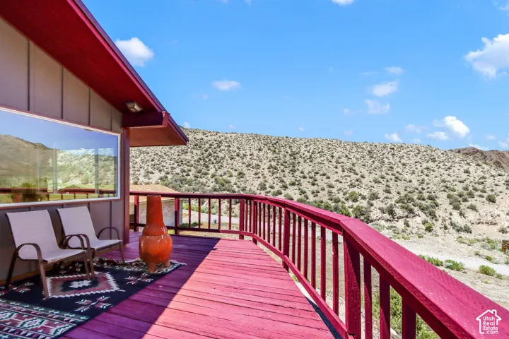 Expansive outdoor deck with a red-stained finish, a curved railing, and a desert landscape backdrop