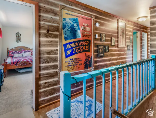 Wood-paneled hallway featuring wood-finish flooring and a painted railing