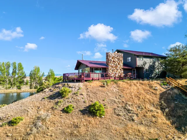 Multi-level residence featuring a metal roof, an expansive outdoor deck, and a stone-clad chimney