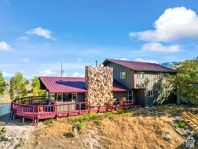 Two-story residence featuring a durable metal roof, extensive exterior decking, and a prominent stone-clad chimney