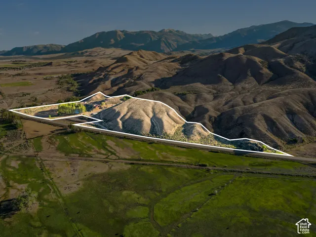 Mountainous landscape with a visible road, a body of water, and a small structure