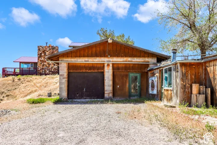 Gravel driveway leading to a two-car garage with wood-paneled siding and a concrete block foundation