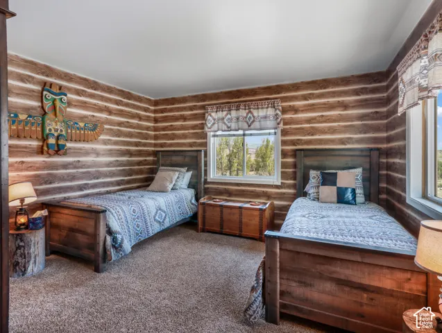 Wood-paneled walls, carpeted flooring, and multiple windows with natural light