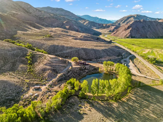 Property featuring a private pond, mature trees, mountainous terrain, and a winding road
