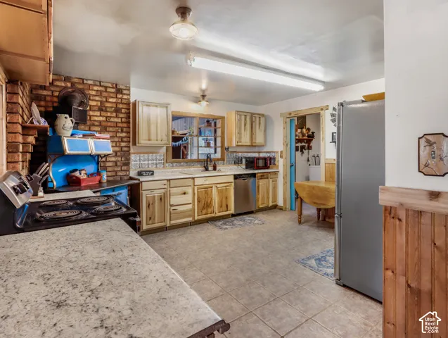 Kitchen featuring a tiled floor, wood-finish cabinetry, light-toned countertops, and a brick accent wall