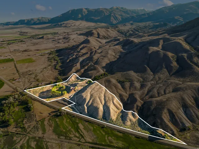 Expansive lot featuring varied terrain, a winding road, and a mountainous backdrop