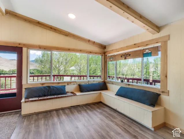 Expansive window wall, wood-finish flooring, built-in bench seating, wood-beamed ceiling, and recessed lighting