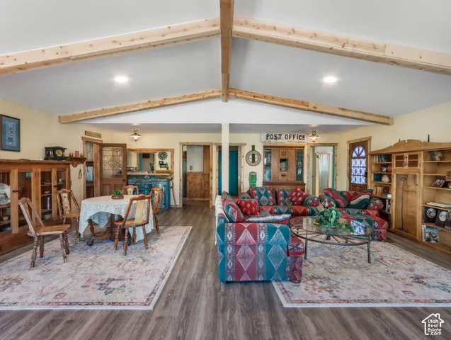 Vaulted ceilings with exposed wood beams, wood-finish flooring, recessed lighting, and built-in shelving
