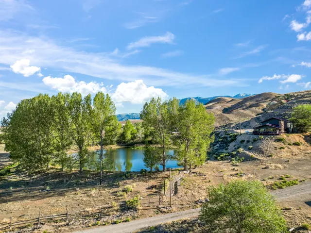 Expansive property featuring a private pond, mature trees, and a dwelling with an exterior deck