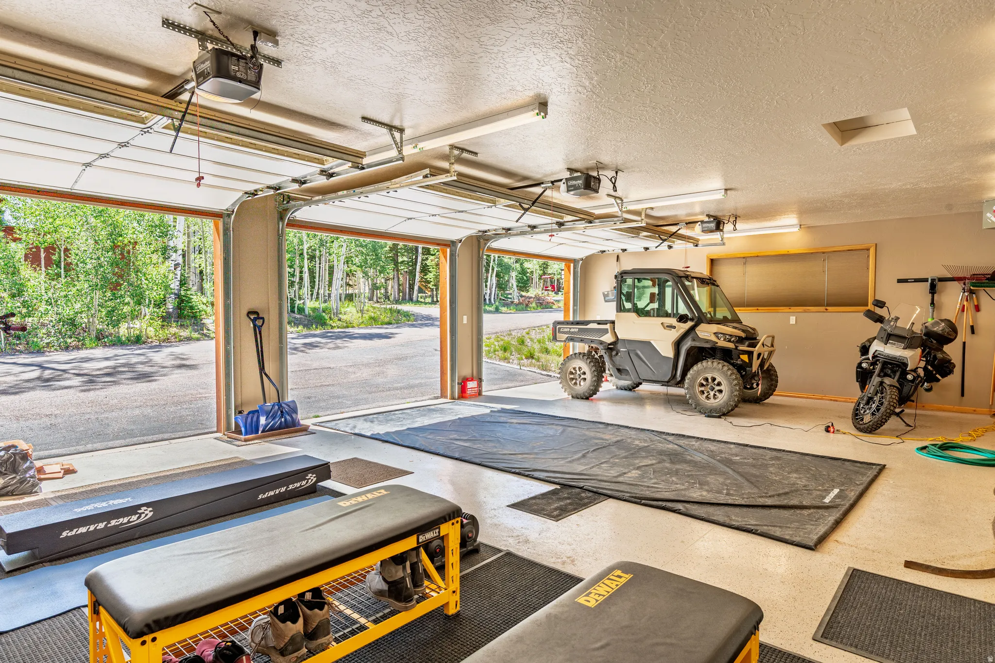 Triple bay garage with overhead doors, finished flooring, and ample lighting