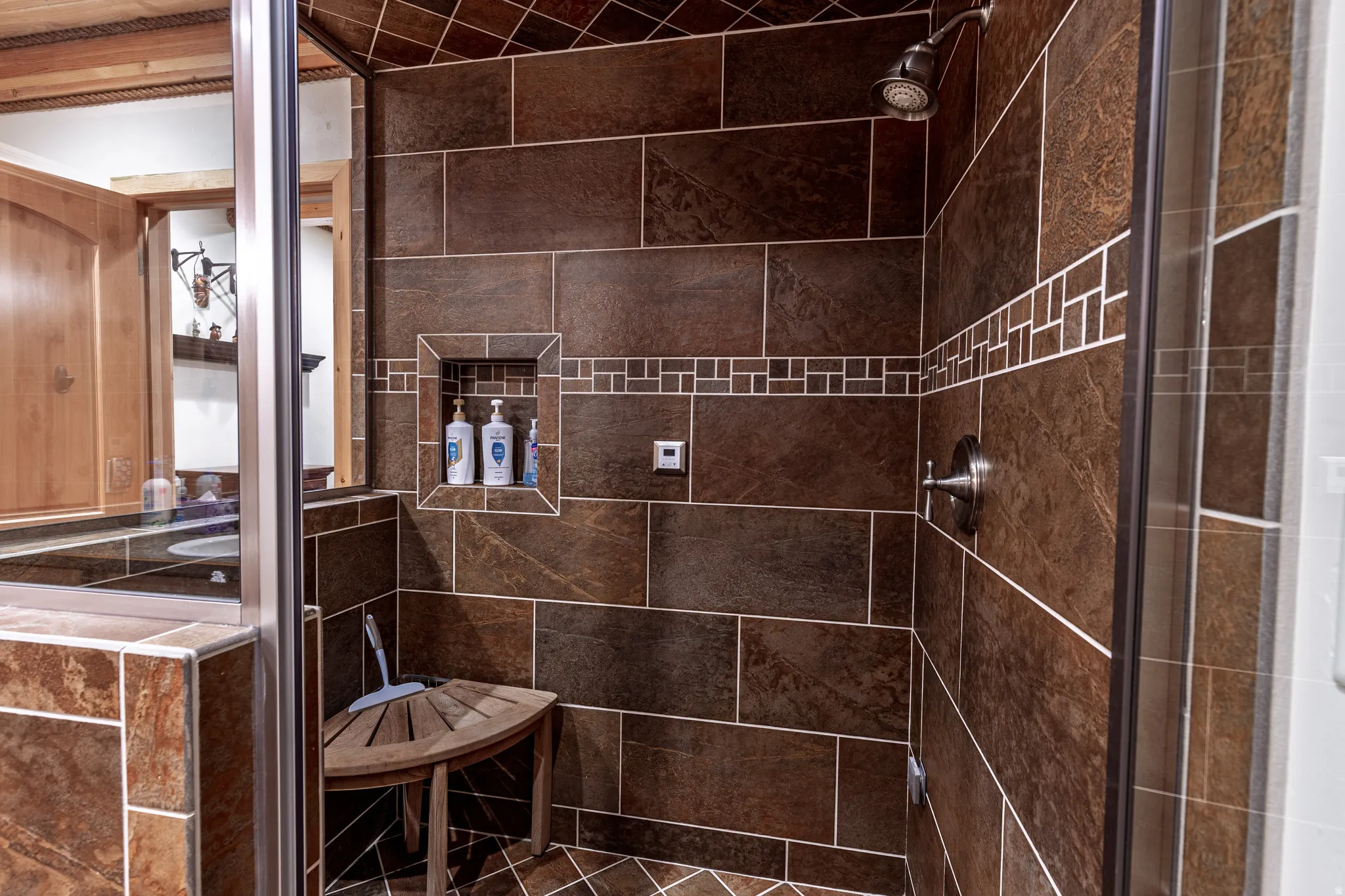 Tiled shower with a mosaic accent band, built-in niche, and brushed nickel fixtures