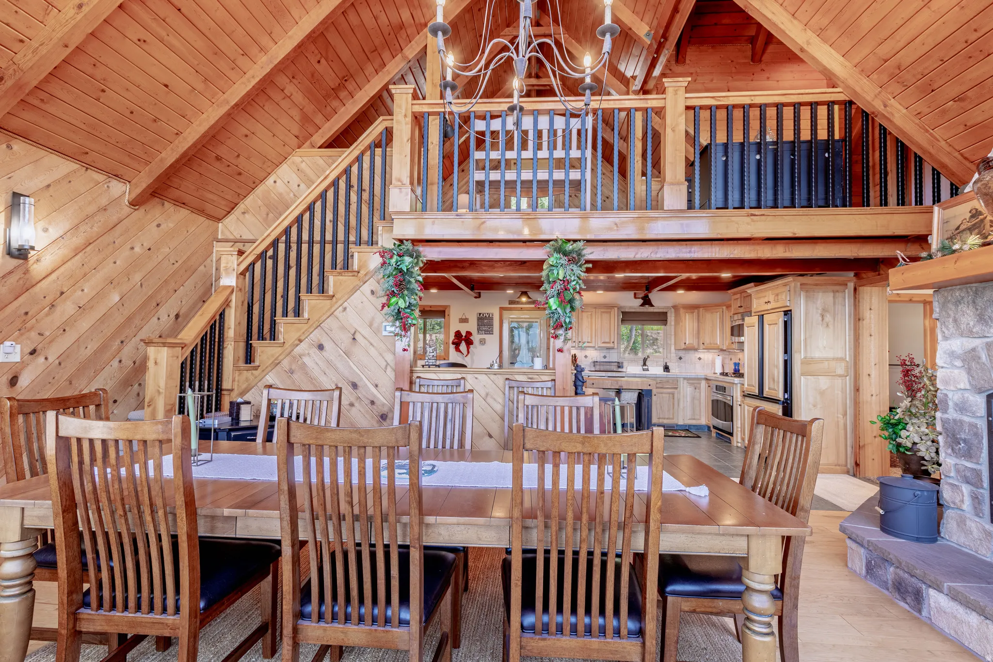 Vaulted wood-paneled ceilings, a stone-faced fireplace, and a wood staircase with black balusters