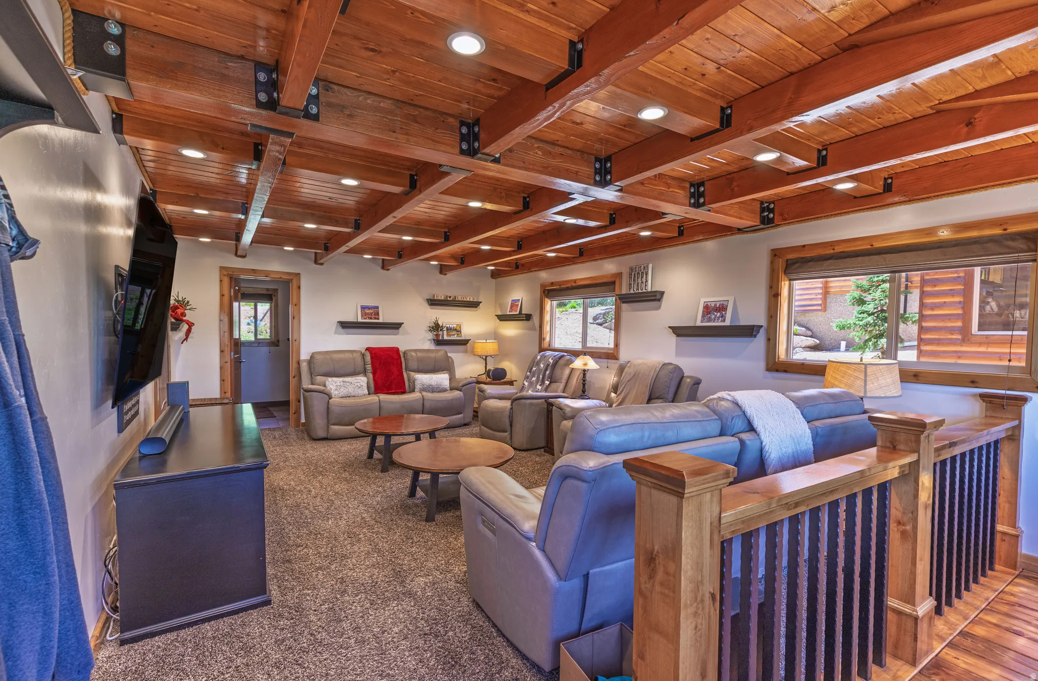 Exposed wood beam ceiling with recessed lighting, wood-trim windows, and wood balusters