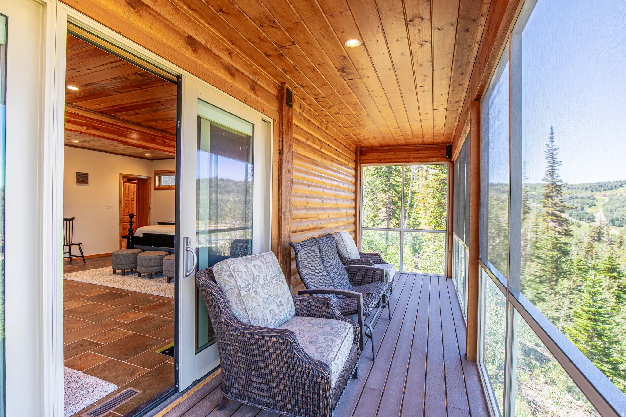 Screened balcony featuring a wood-plank ceiling and decking