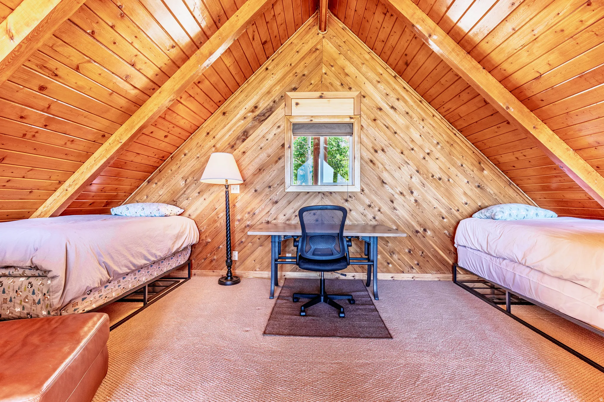 Wood-paneled sloped ceilings, exposed wooden beams, and a centered window