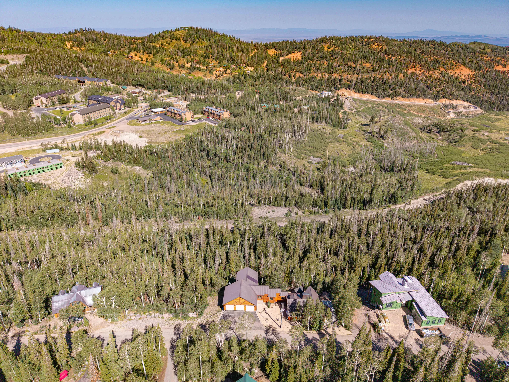 Expansive mountain landscape featuring dense forest and scattered residential structures