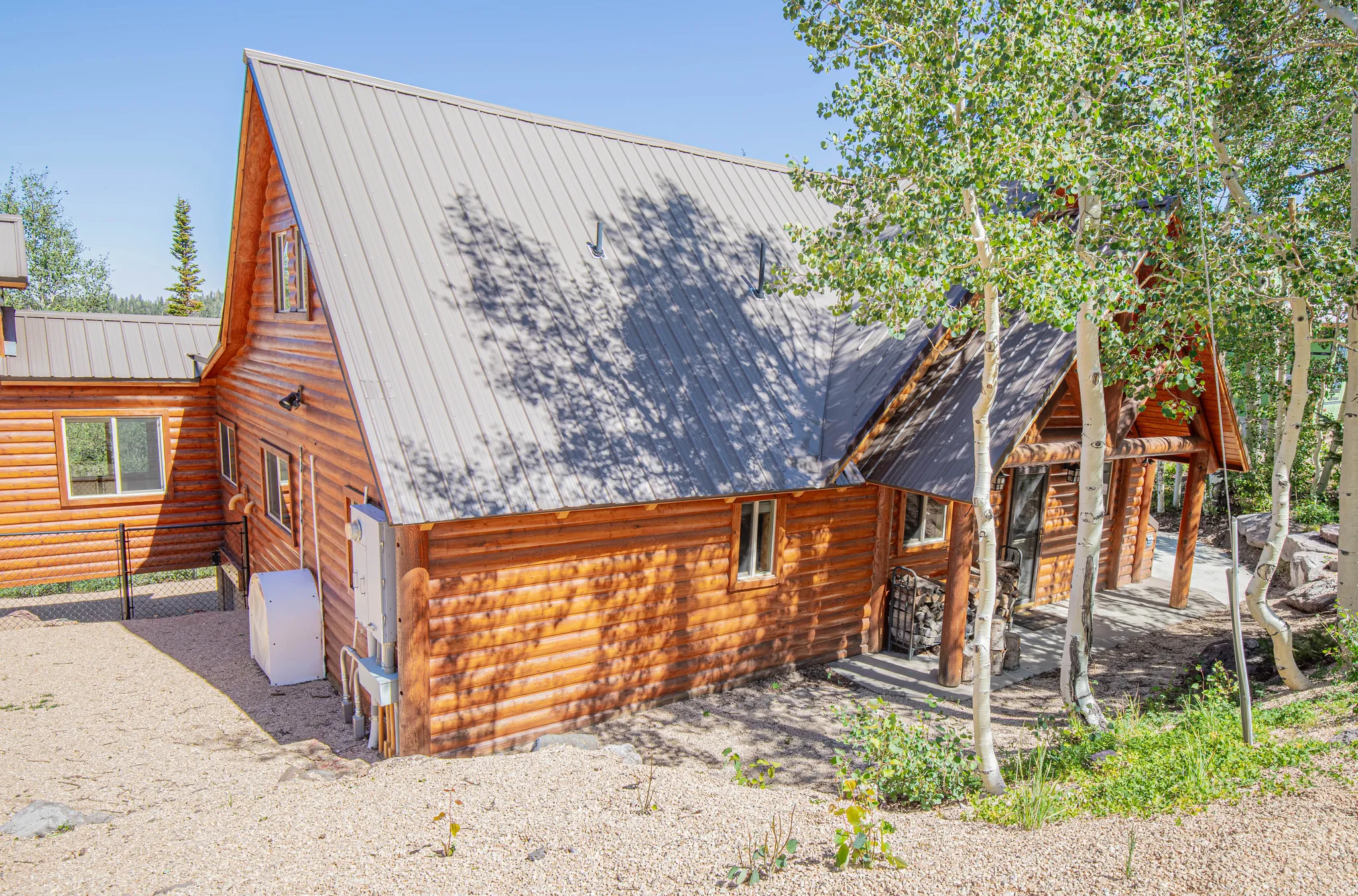 Log-sided residence featuring a gray metal roof, multiple windows, and a covered entry